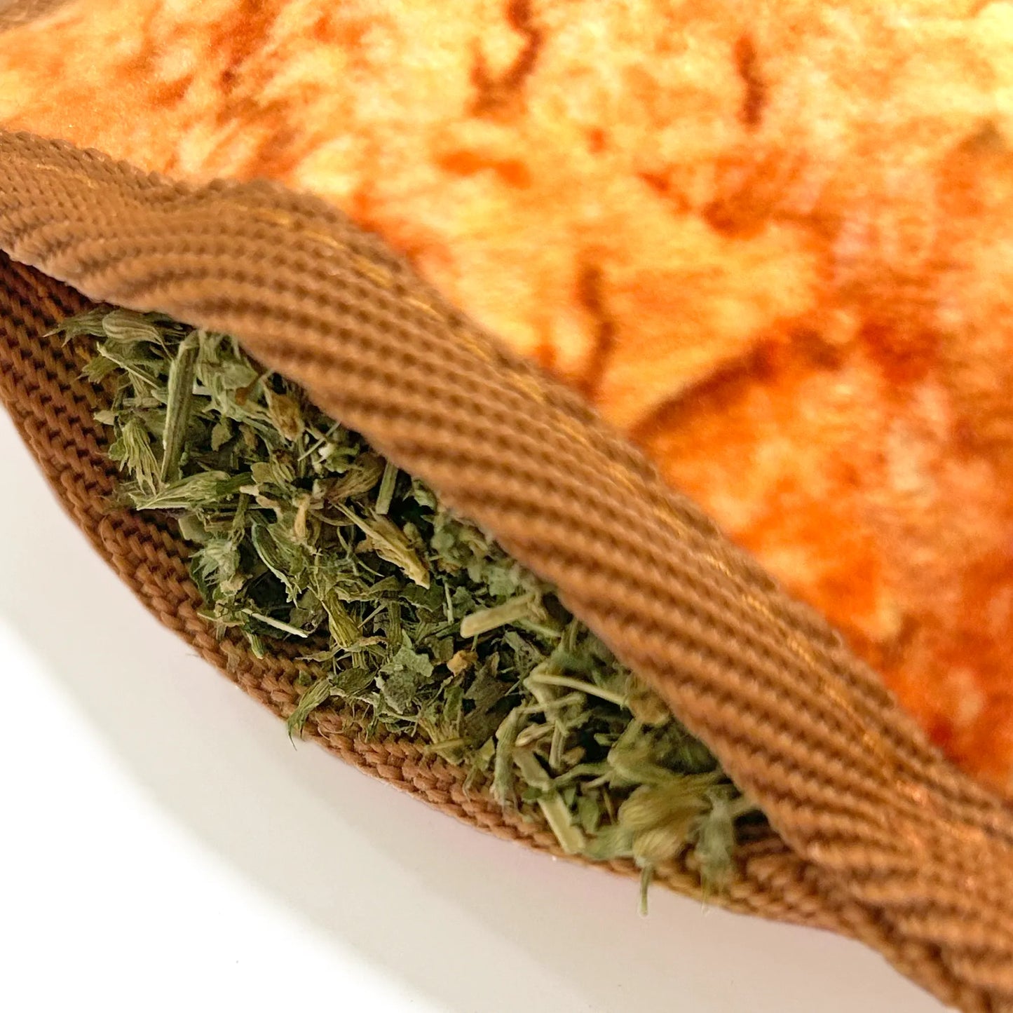 Close-up of the Juananip® Tuffer Chewer toy showing its refillable pocket filled with catnip for interactive play.